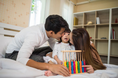 Parents kissing daughter on cheek at home