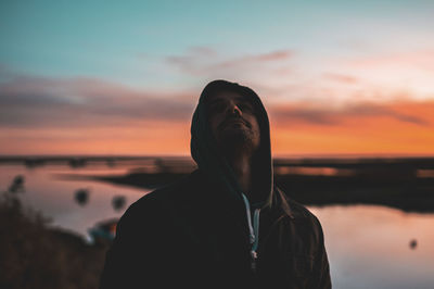 Portrait of man standing against sea during sunset