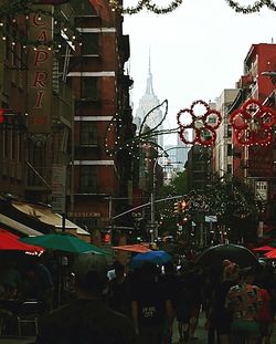 People on city street amidst buildings against sky