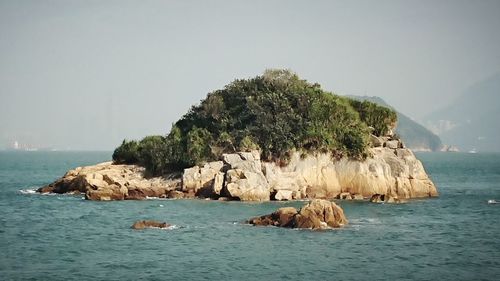 Rock formation in sea against clear sky