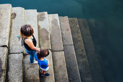 High angle view of mother and daughter standing on steps by lake