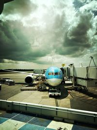 Airplane on airport runway against cloudy sky