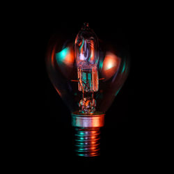 Illuminated light bulb against black background