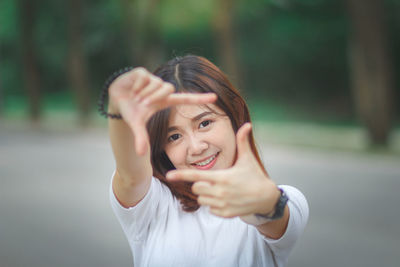 Portrait of smiling young woman making finger frame