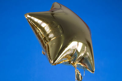 Golden star shape helium balloon against blue background