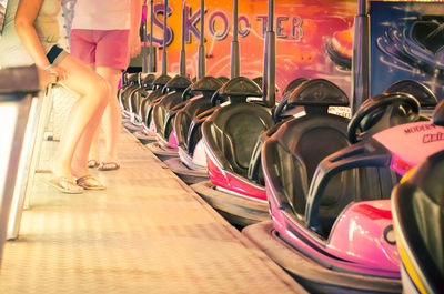 Low section of friends against bumper cars at amusement park