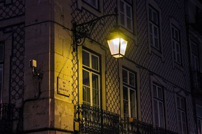Low angle view of illuminated lamp against building at night