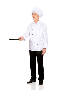 Mature chef holding skillet pan against white background