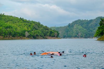 People swimming in sea against sky