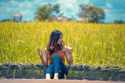 Full length of woman sitting on field