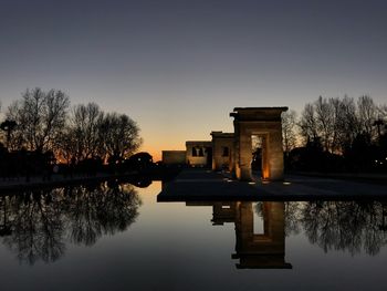 Reflection of silhouette trees in lake against sky during sunset