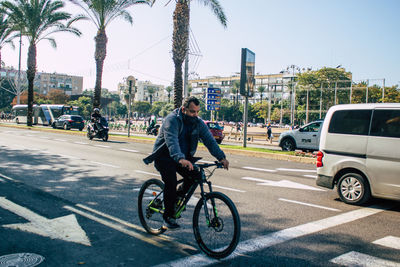 Man riding bicycle on road in city