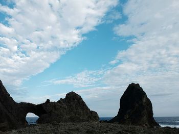 Rock formation at beach against sky