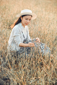 Thoughtful mid adult woman relaxing on grassy field