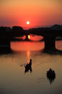 Silhouette person in boat against sky during sunset