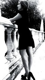 Side view of woman standing against built structure