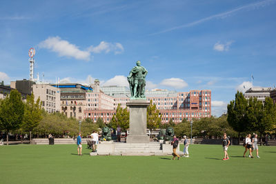 People by statue at kungstradgarden in city