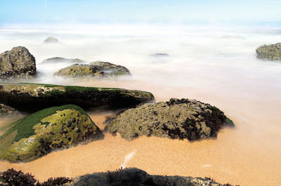 Scenic view of rocks on beach against sky