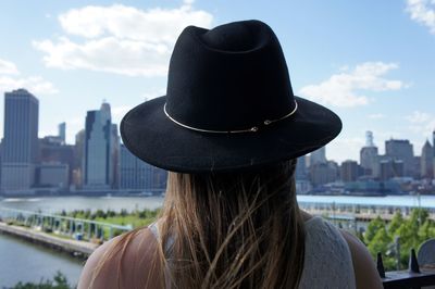 Rear view of woman looking at cityscape against sky