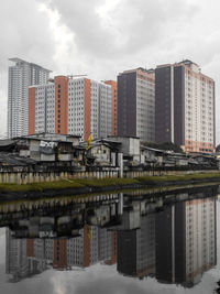 Bridge over river by buildings against sky in city