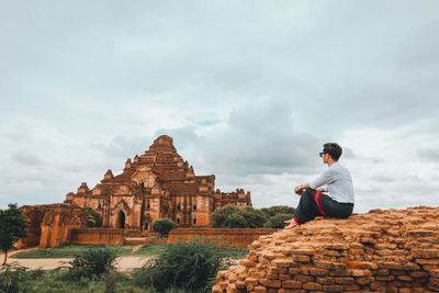 Man sitting on temple against sky