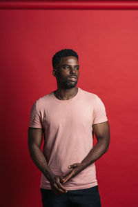 Portrait of young man standing against red background