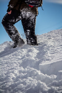 Low section of person on snowcapped mountain against sky