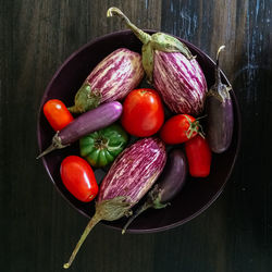 Directly above shot of tomatoes with eggplants and chili peppers in bowl