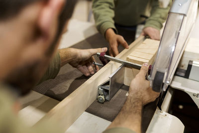 Male carpenters working with carpentry equipment at workbench in industry