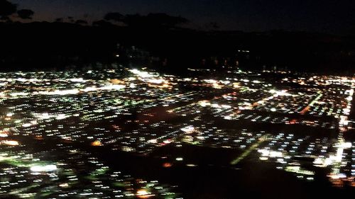 Illuminated cityscape against sky at night