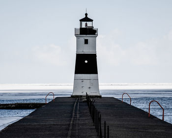 Lighthouse by sea against sky