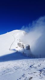 Scenic view of snow covered land against blue sky