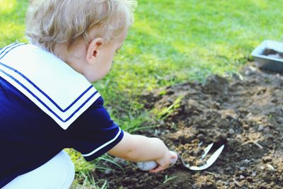 Baby boy digging with gardening fork on ground