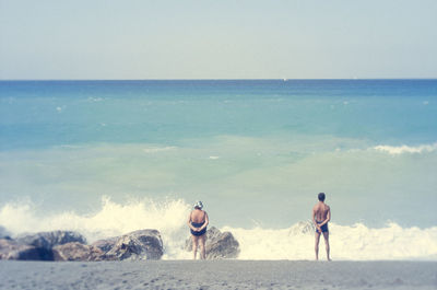 Men on beach against clear sky