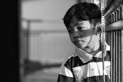 Close-up of boy looking away while standing by fence