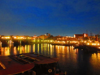River by illuminated city against sky at night