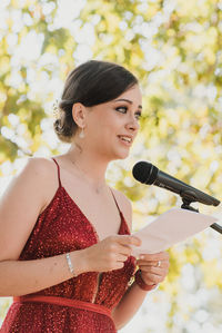 Smiling woman reading letter by microphone