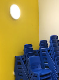 Empty blue chairs against yellow wall