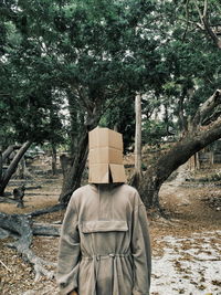 Man wearing box on head while standing in the forest