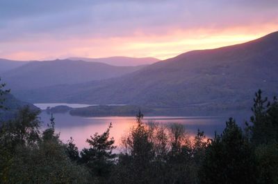 Scenic view of lake and mountains against sky at sunset