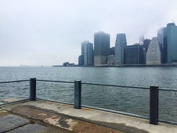 Sea by cityscape against sky