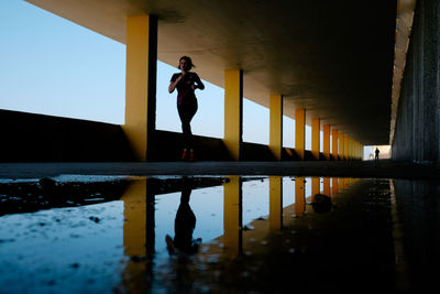 Reflection of woman standing on puddle