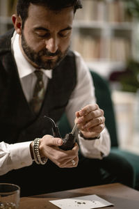 Bearded man preparing smoking pipe