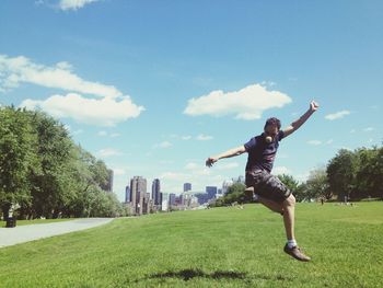 Woman playing on field in park against sky