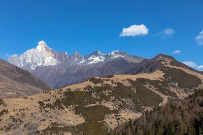 Scenic view of snowcapped mountains against blue sky