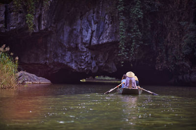 Rear view of woman on rock formation in water