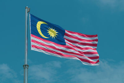 Low angle view of flag against blue sky