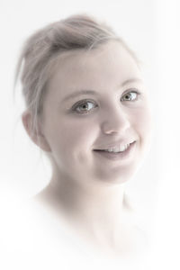 Close-up portrait of smiling teenage girl against white background