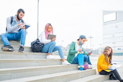 Friends sitting staircase against building