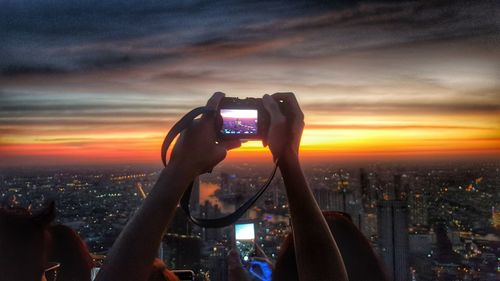 Woman photographing cityscape at sunset